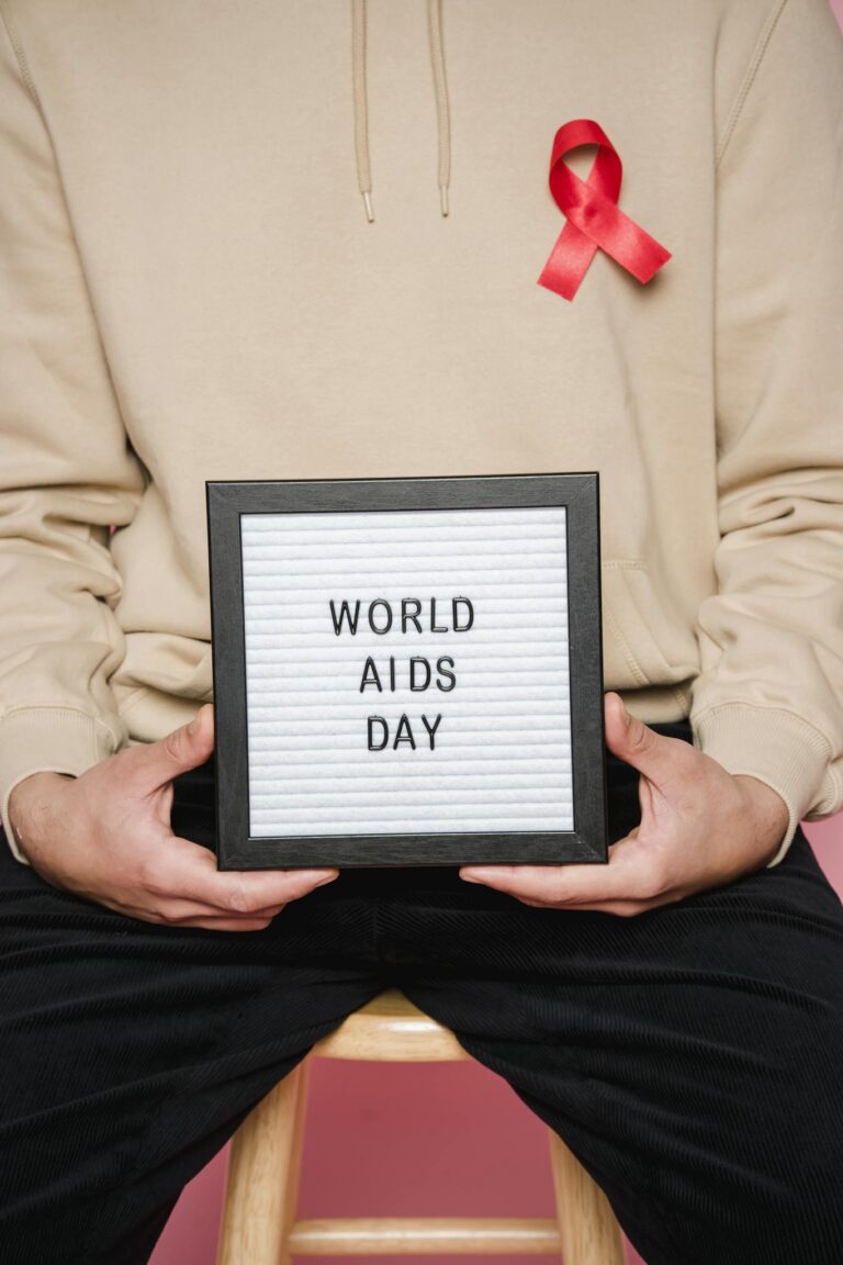 Person holding World AIDS Day sign with a red ribbon for awareness.