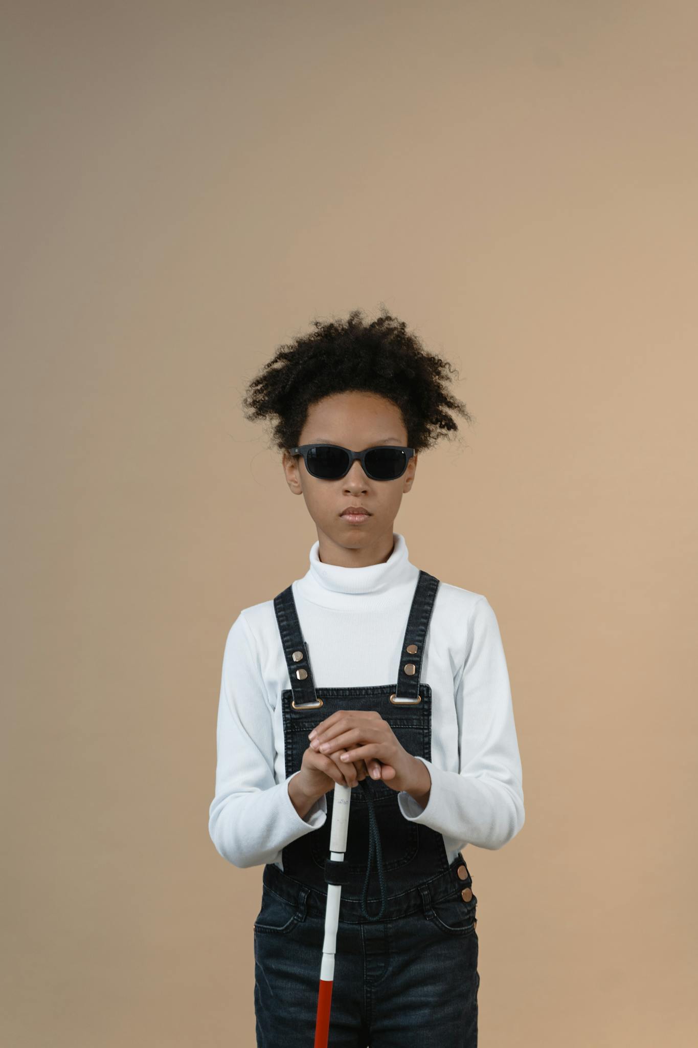 Portrait of a girl with sunglasses and cane, symbolizing strength and independence.
